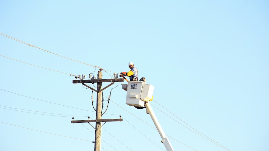utility lineman climbing wooden power pole